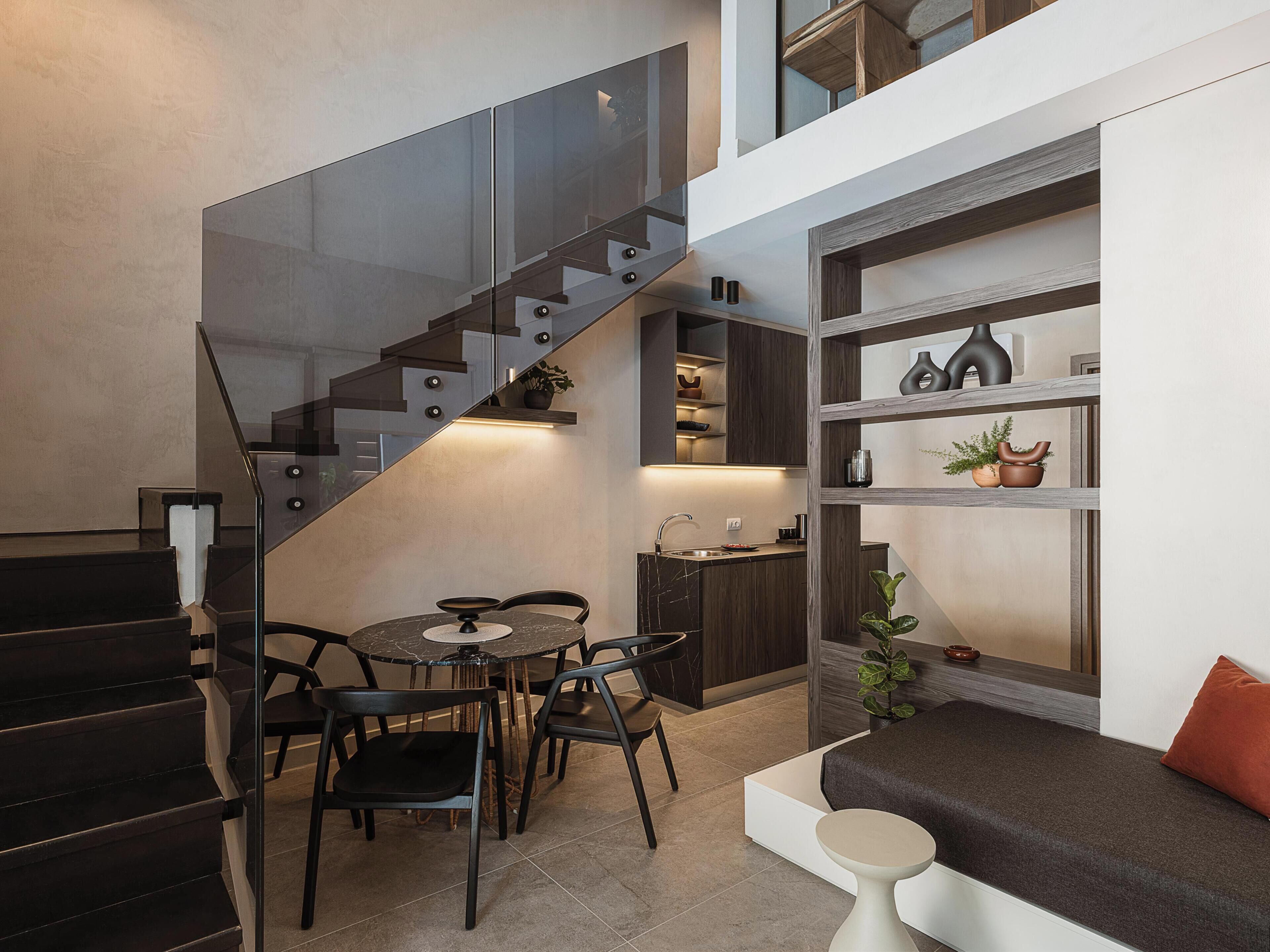 A modern interior with a staircase, dining area, and built-in shelving.