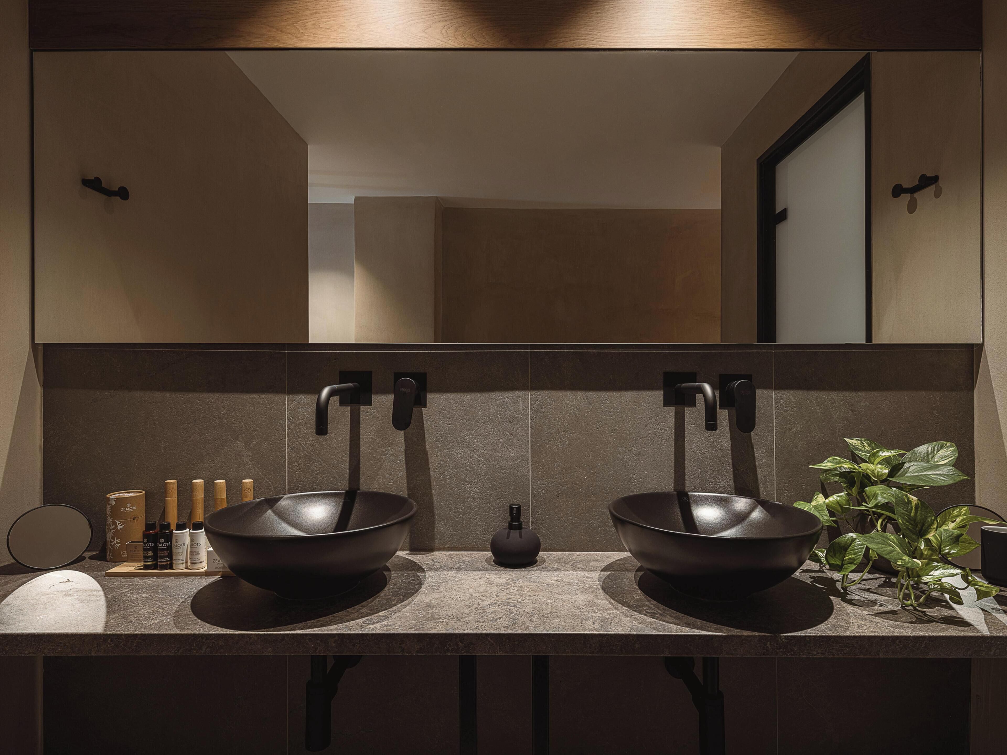 Un baño moderno con lavamanos doble, un espejo grande y una planta en maceta.