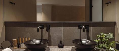 A modern bathroom with a double sink, large mirror, and a potted plant.
