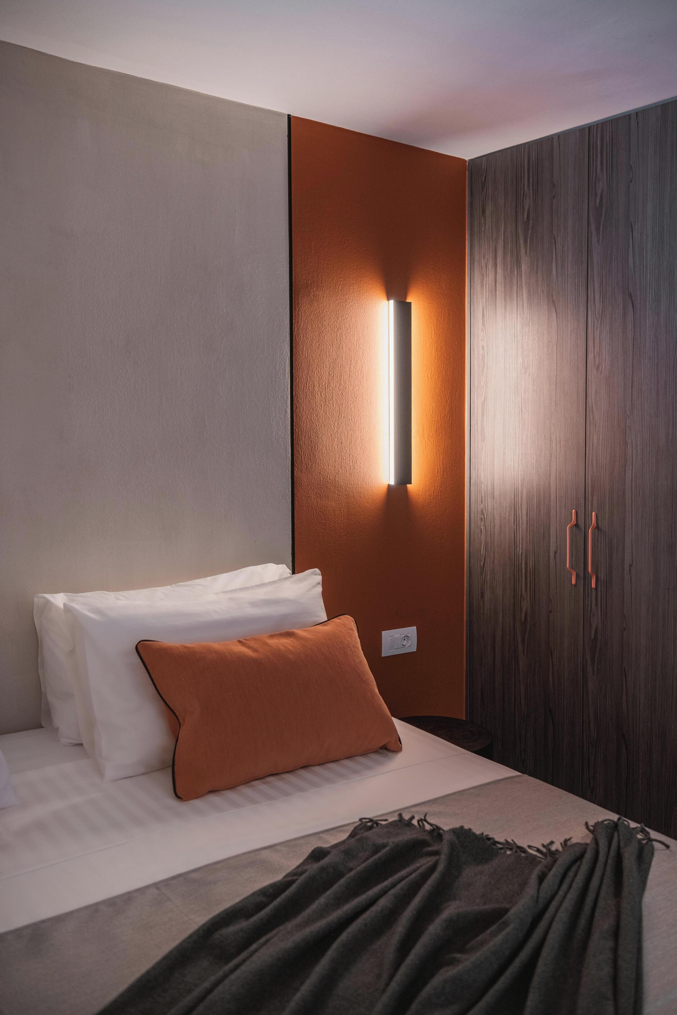 A bedroom with a bed, a wall-mounted light, and a wardrobe.