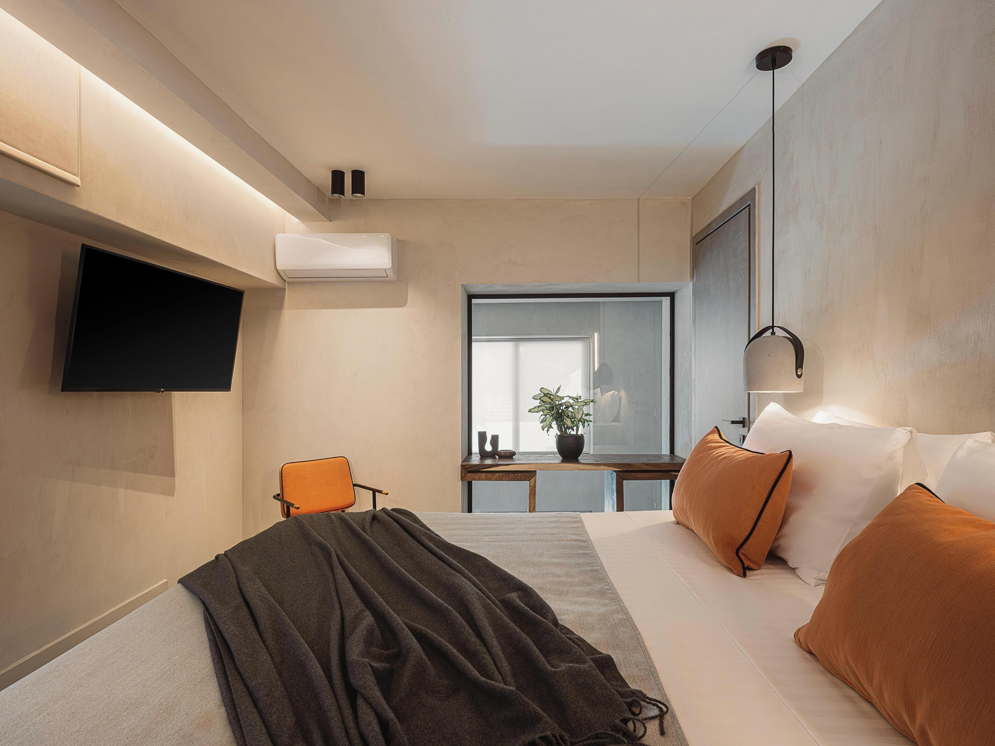 Una habitación de hotel moderna con una cama, un televisor de pantalla plana, un escritorio con una silla y un ventanal grande.