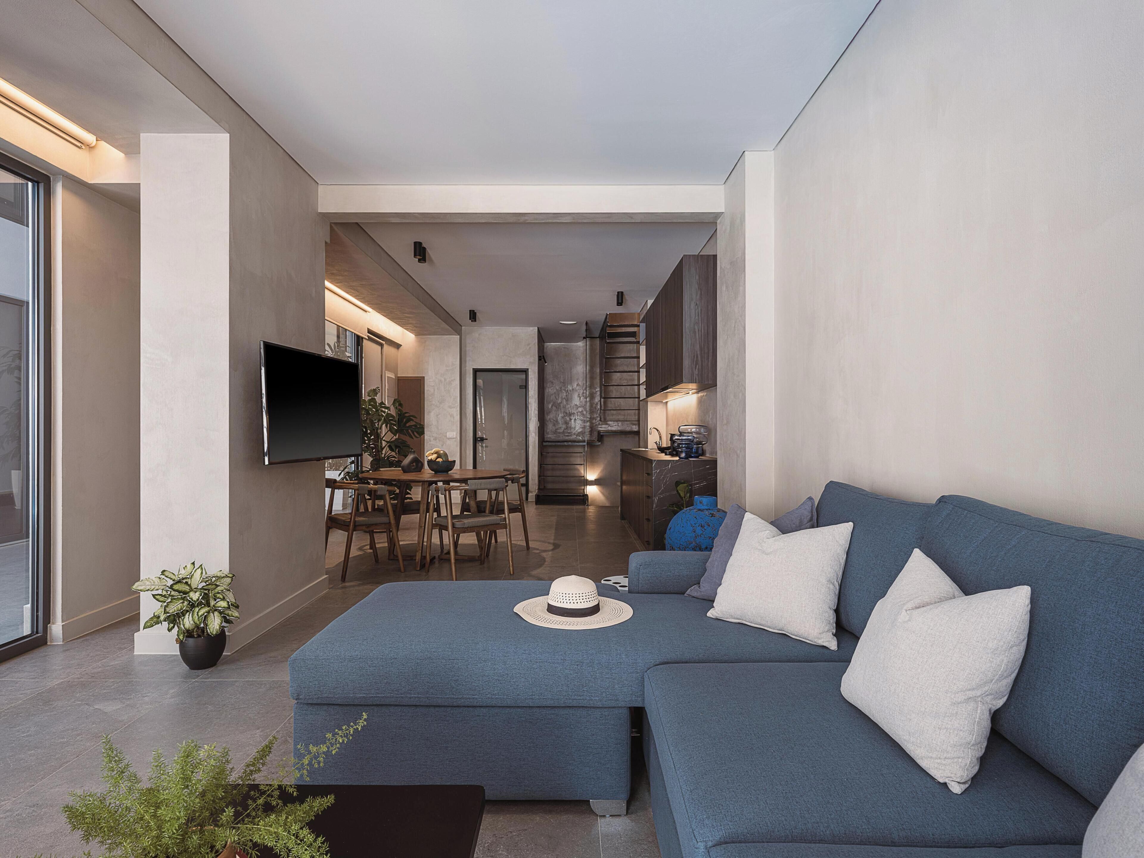 A modern living room with a sectional sofa, a dining area, and a kitchen.