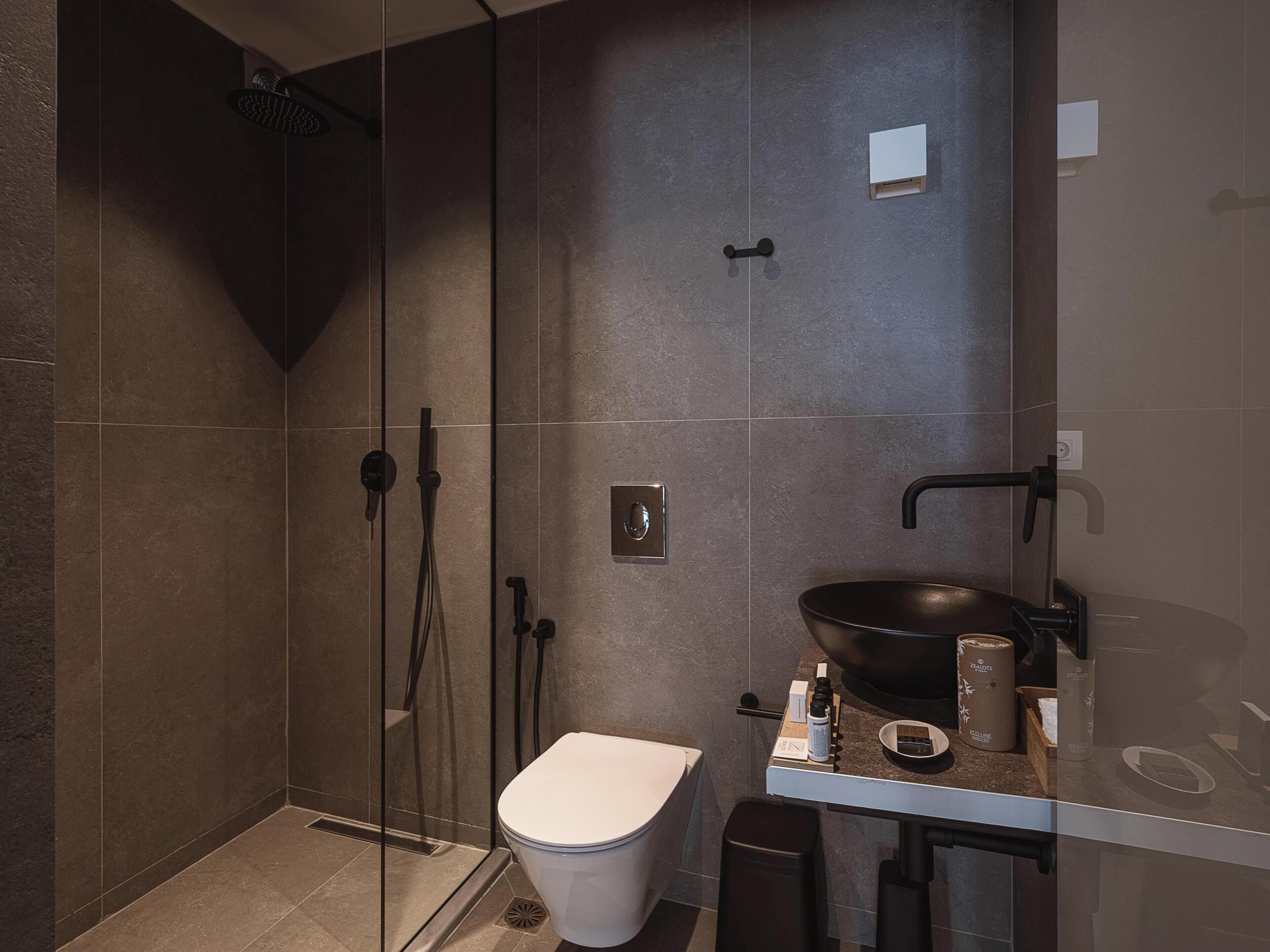 Un baño moderno con cabina de ducha de vidrio, inodoro y lavamanos de gran tamaño.