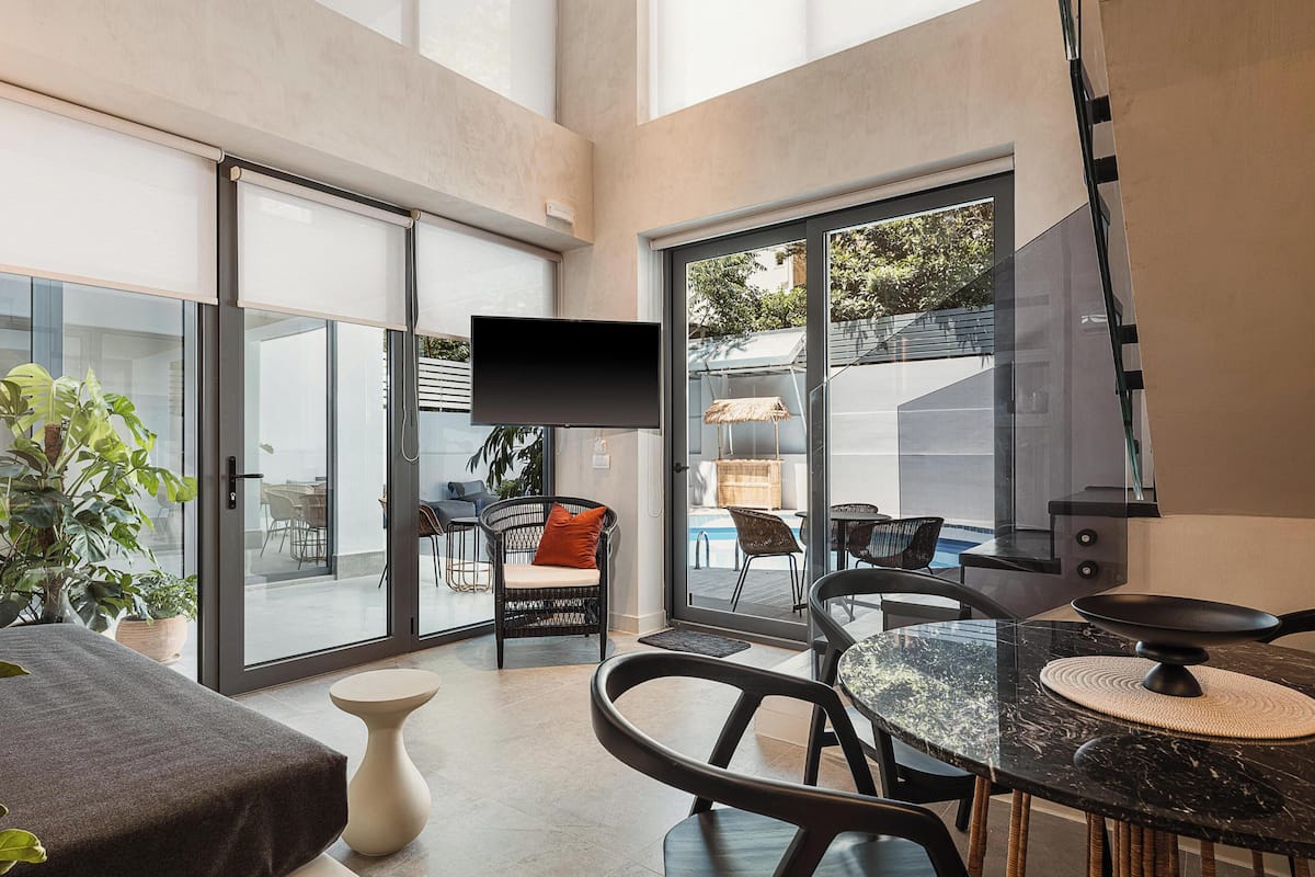 Un interior moderno con comedor, televisor y vistas al exterior.
