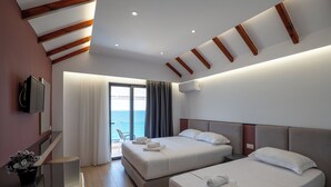 A hotel room with two beds, a TV, a desk, and a view of the sea. - Hotel Emblem (Sarandë)