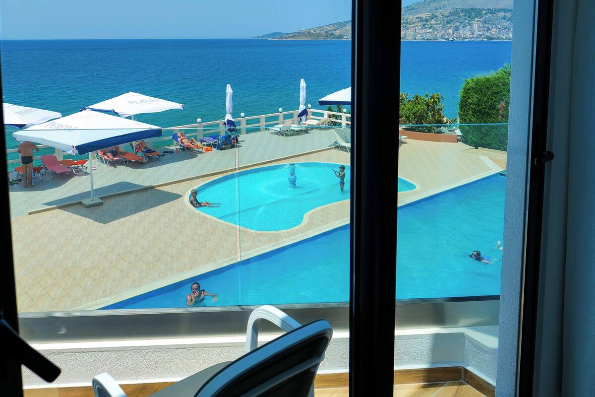 A balcony with a view of a swimming pool and the sea.