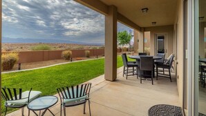 A covered patio with a view of a grassy yard and distant mountains. - Desert Escape: Sand Dunes + Golf + Resort Access (Hurricane)