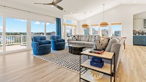 Uma sala de estar ampla, com um sofá grande, poltronas azuis e um ventilador de teto.
