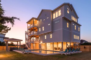 Une maison à plusieurs étages dotée d’un balcon, d’une piscine et d’un espace salon extérieur.