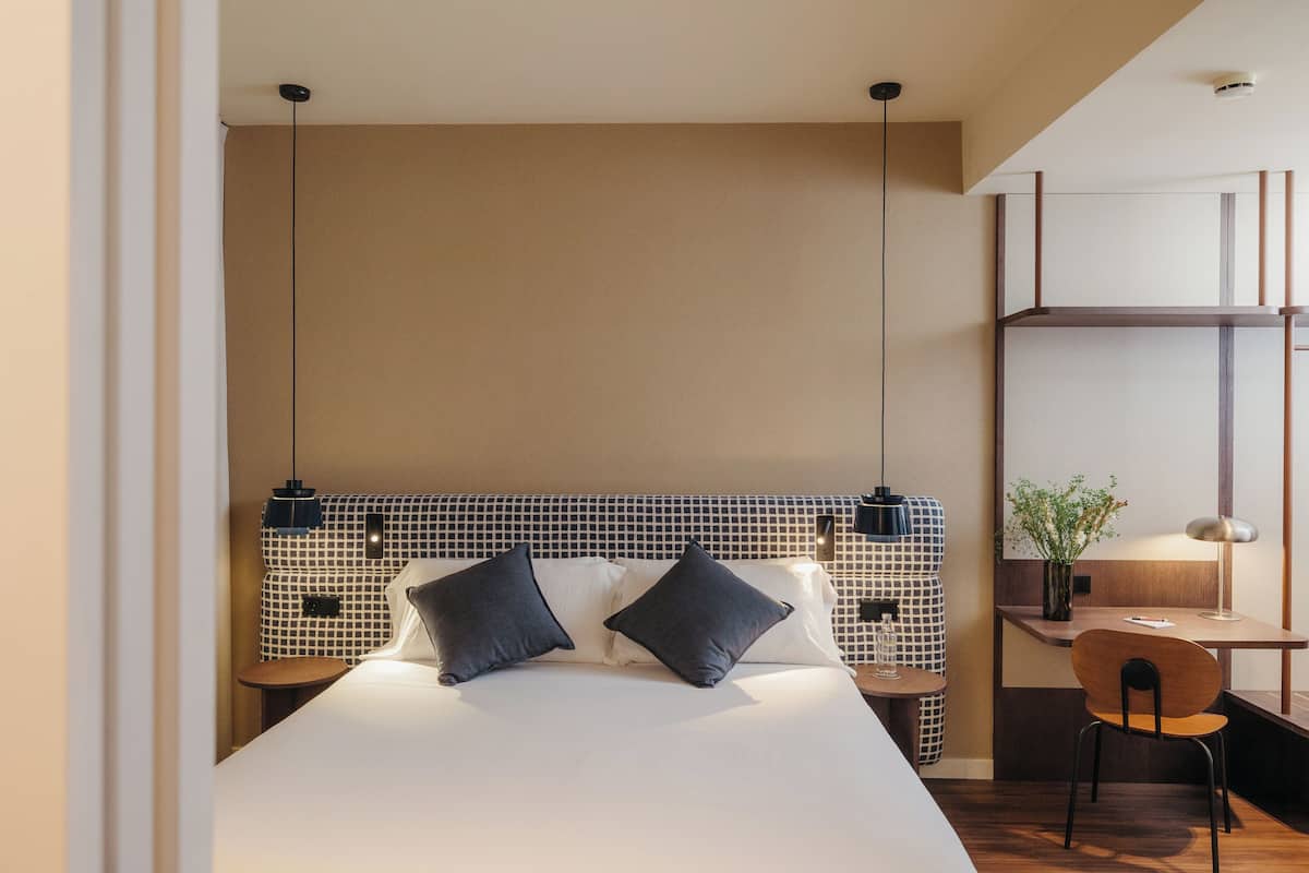 Una habitación de hotel moderna con una cama grande, un escritorio y una silla.