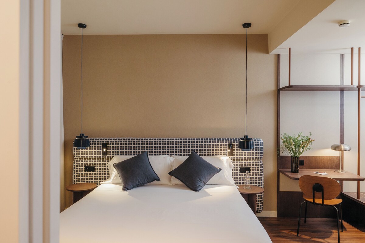 Una habitación de hotel moderna con una cama grande, un escritorio y una silla.