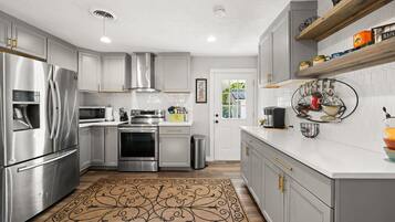 A modern kitchen with stainless steel appliances, white cabinetry, and a patterned rug.