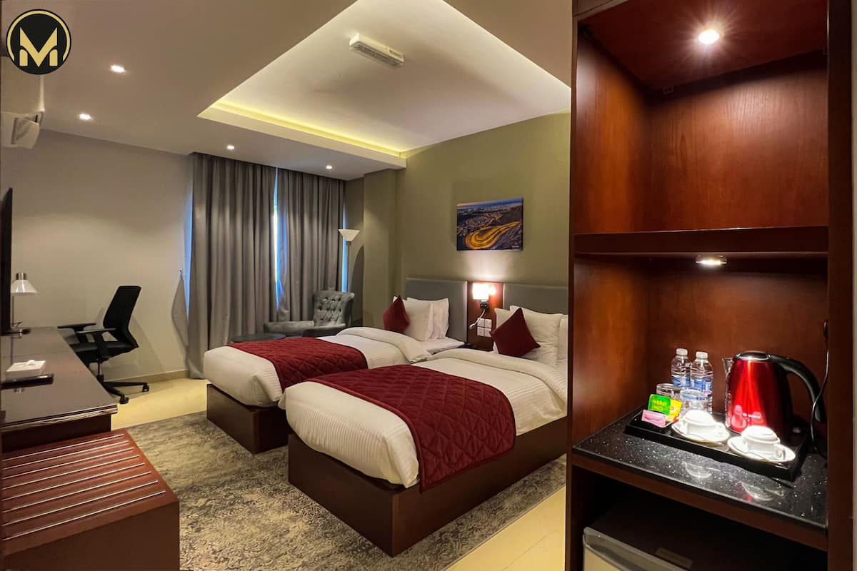 Habitación de hotel con dos camas, un escritorio, una silla, un televisor y un minibar.