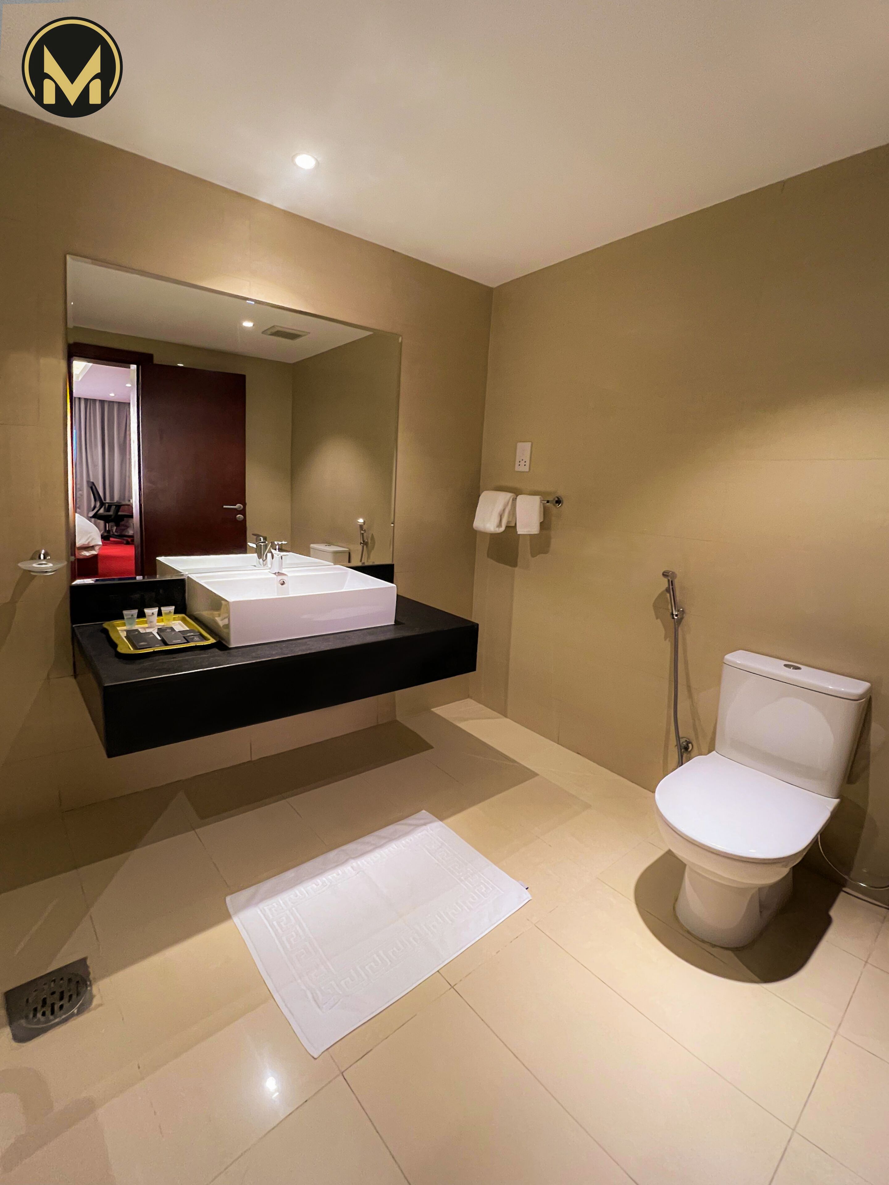 A modern bathroom with a large mirror, a white sink, a toilet, and a shower.