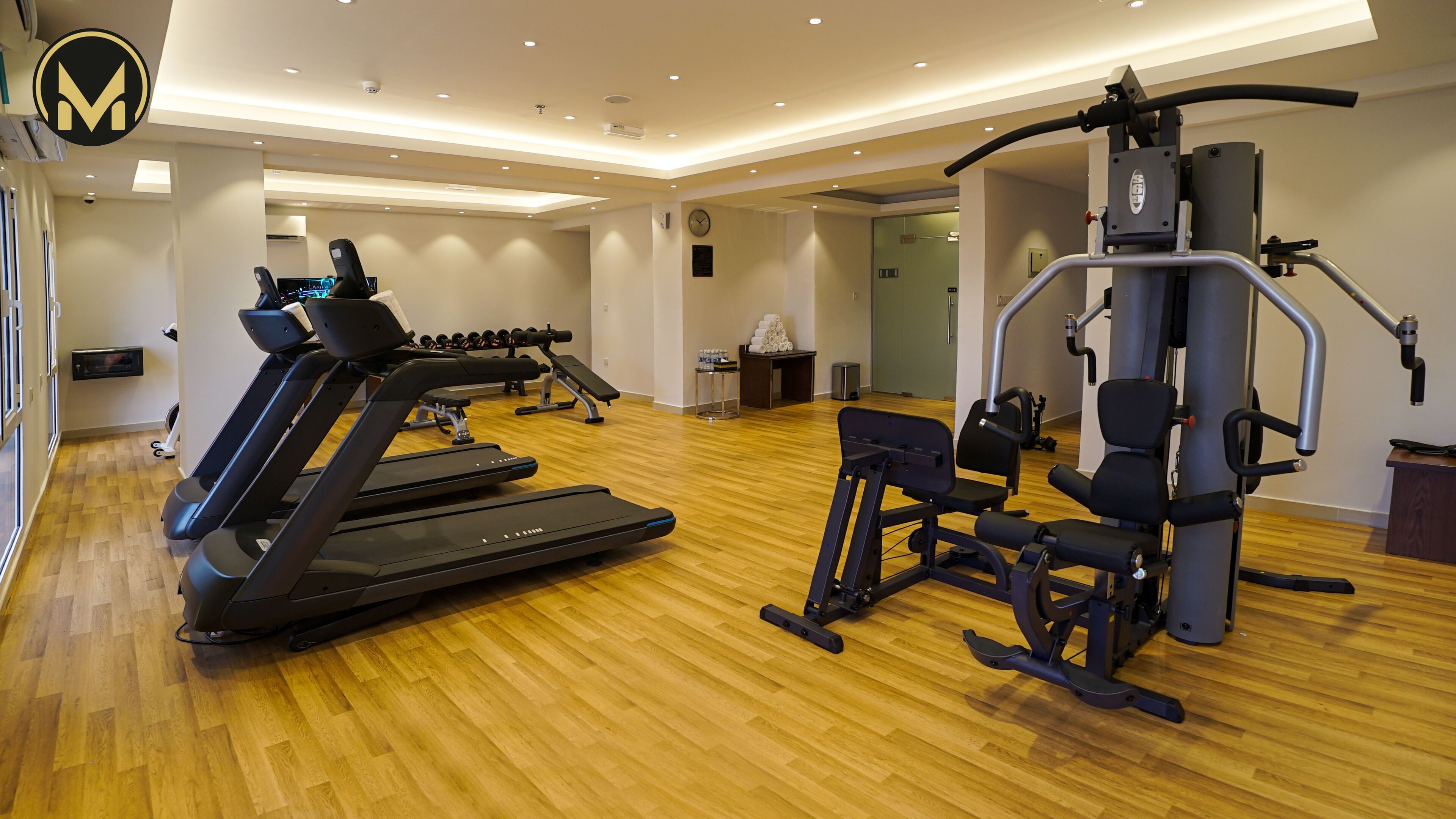 Un gimnasio con cintas de correr, máquinas de pesas y un reloj de pared.