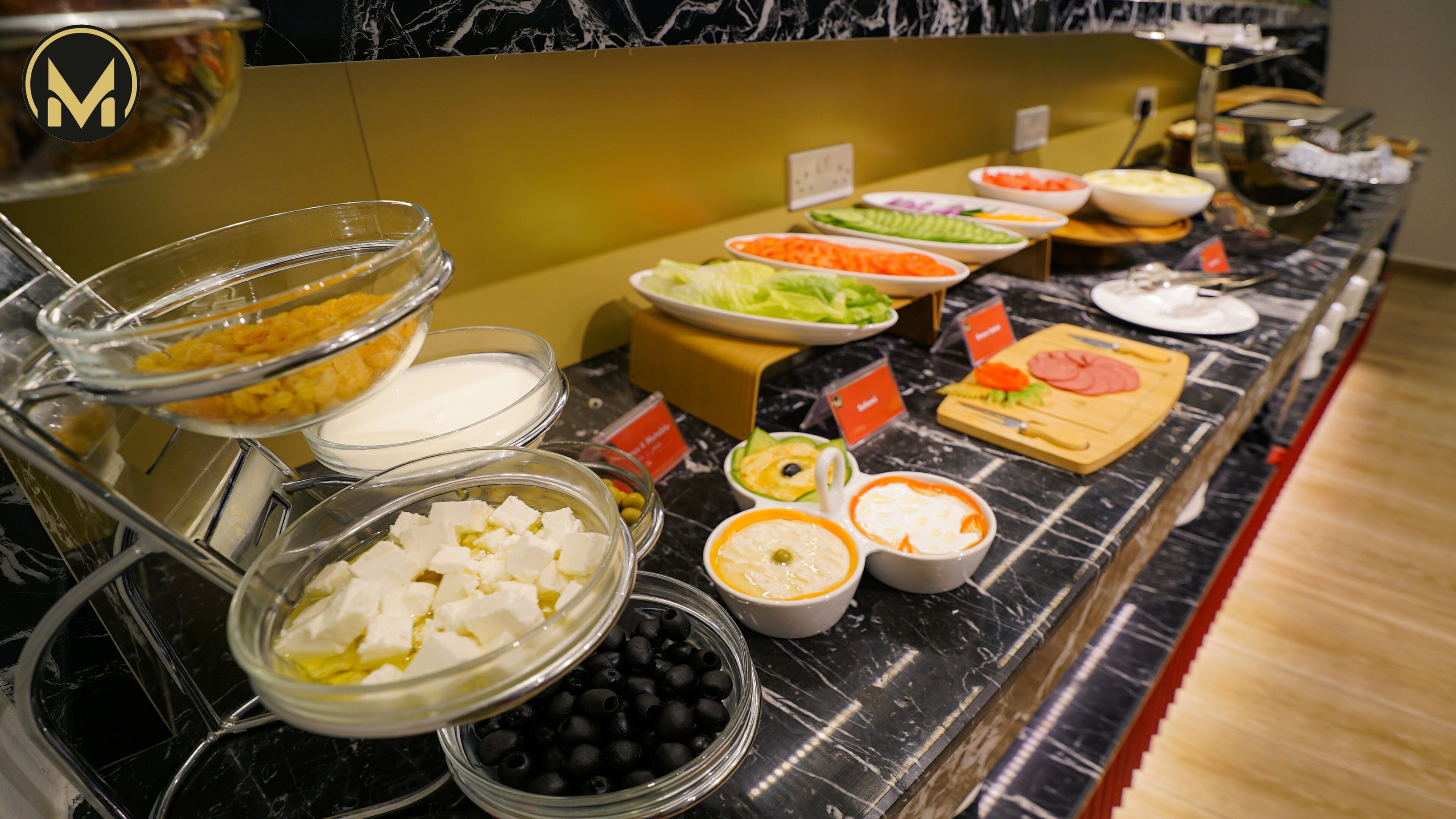 A buffet with various food items including cheese, olives, and vegetables.