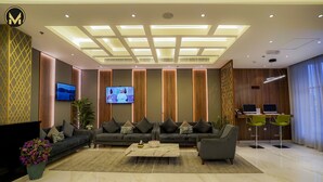 A modern lobby with a seating area, a reception desk, and a TV screen. - Muscat Express Hotel (Muscat)