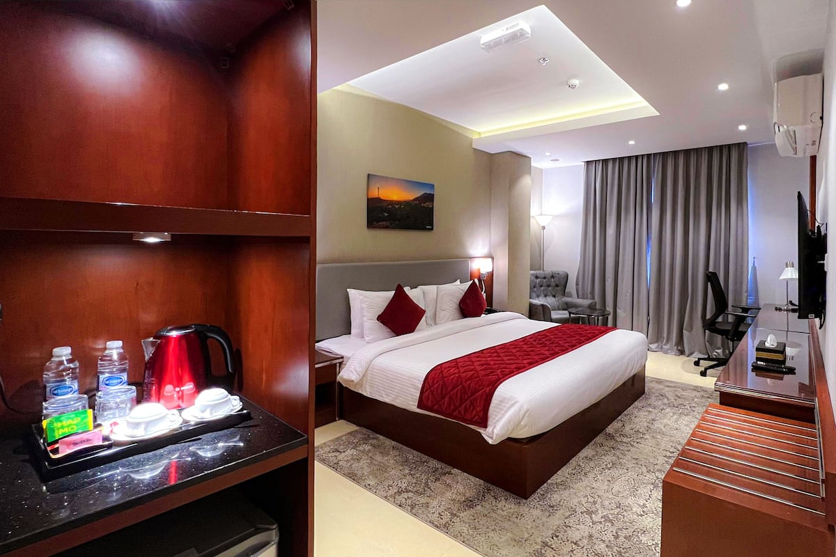 Una habitación de hotel con cama, escritorio, silla, televisor y minibar.