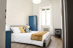 Un dormitorio con cama, armario, radiador y ventana.