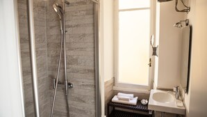 Une salle de bain avec une douche, un lavabo et une fenêtre.