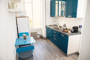 Una cocina compacta con una mesa y sillas azules, un fregadero y un hervidor.