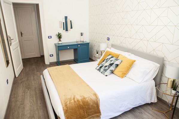 Un dormitorio ordenado con cama, mesitas de noche y un escritorio.