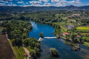 Un río que atraviesa un valle, con casas a la derecha y un bosque denso a la izquierda.