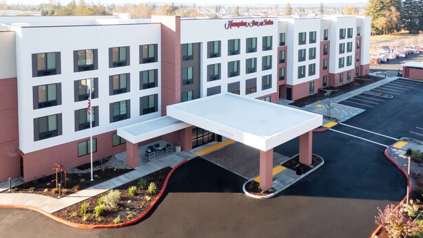 A modern hotel with a flat roof, multiple windows, and a covered walkway.