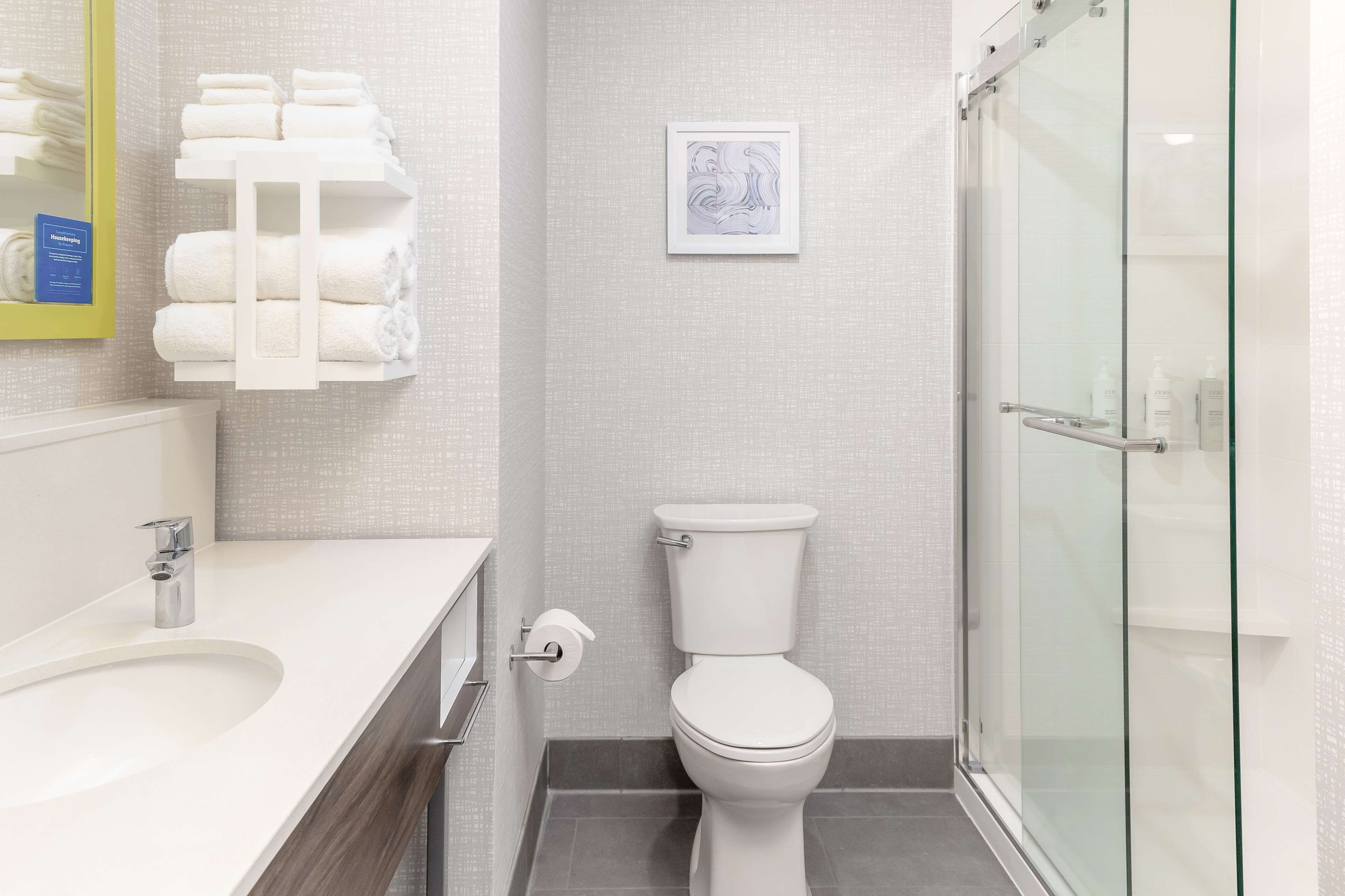 A modern bathroom with a white sink, a toilet, and a glass shower enclosure.