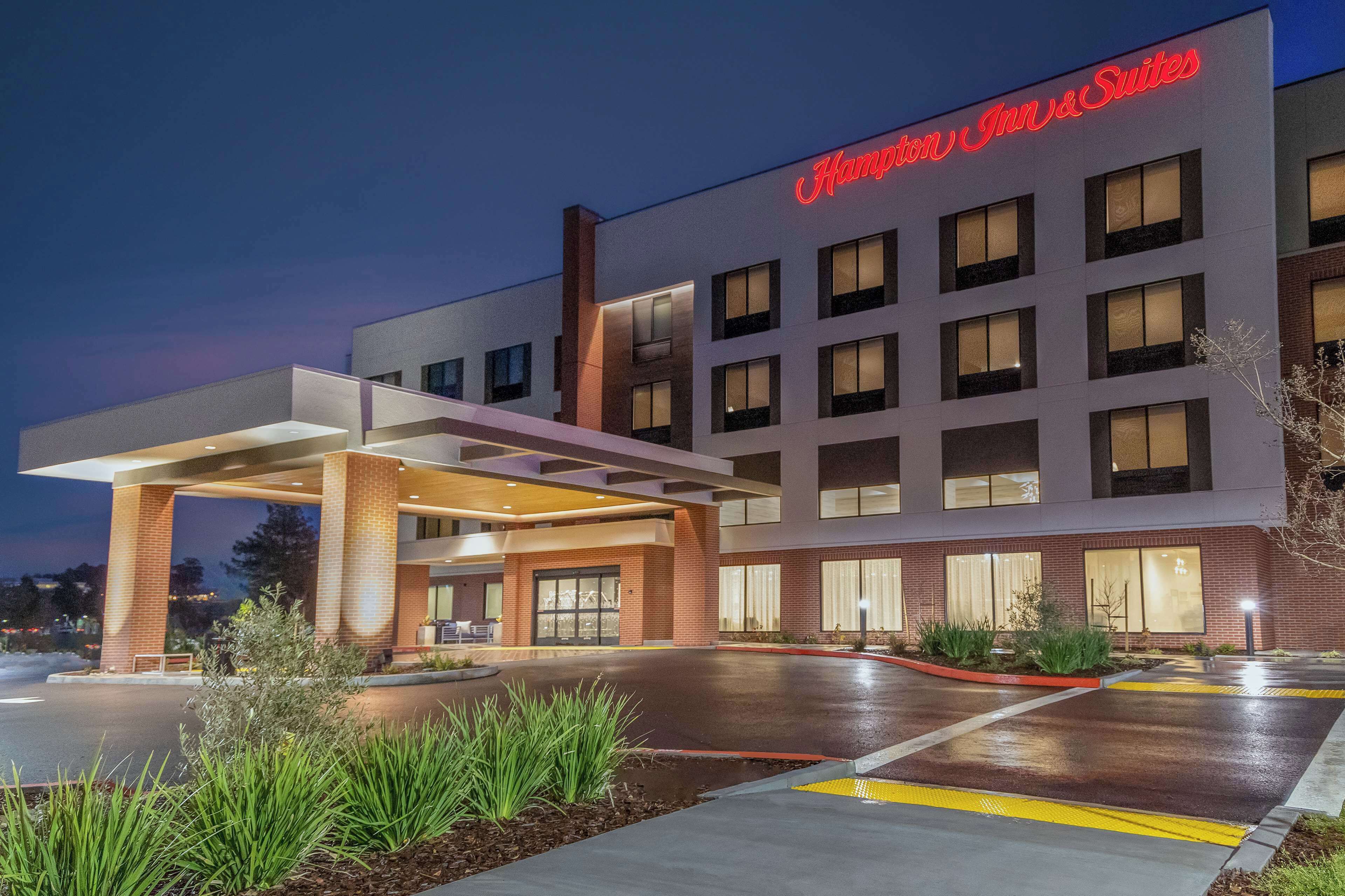 A modern hotel with a prominent sign reading "Hampton Inn & Suites."