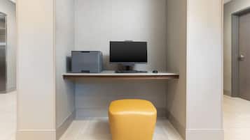 A modern office space with a desk, computer, printer, and a yellow ottoman.