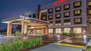 Et Hampton Inn & Suites hotel med moderne design, inklusive en overdækket indgang og en veloplyst facade.