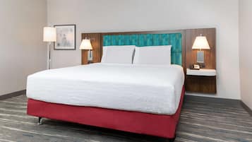 A hotel room with a large bed, two bedside tables with lamps, a framed picture on the wall, and a patterned carpet.