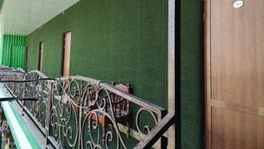 A building exterior with a green wall, a wooden door marked with the number 204, and a metal railing with ornate designs. - Green House Hotel (Bukhara)