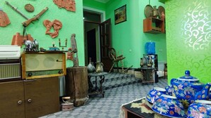 A room with a green wall, a typewriter, wooden furniture, and blue floral-patterned tea sets. - Green House Hotel (Bukhara)