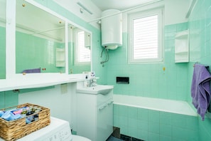 Une salle de bain avec un lavabo blanc, un miroir, des toilettes et une baignoire.