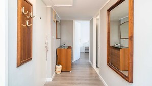 Un pasillo con puertas de madera, un escritorio pequeño y un espejo.