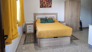 A bedroom with a bed, nightstand, wardrobe, and a wall art piece. - NIGRAN, Studio 10 minutes from Playa America (NIGRAN)