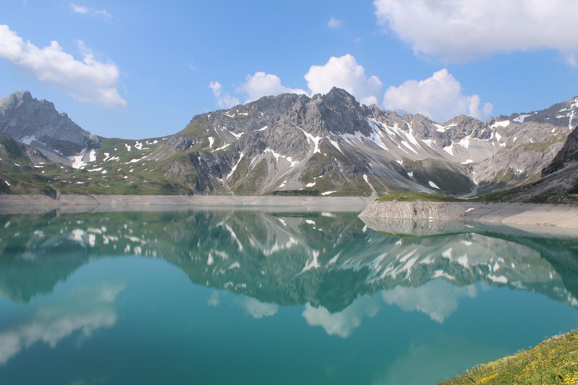 Un paysage de montagne avec un lac aux eaux claires dans lequel se reflètent les montagnes.