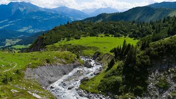 A mountainous landscape with a river, green fields, and distant mountains.
