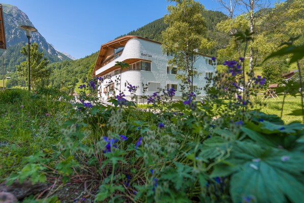 Un hotel de diseño moderno, rodeado de vegetación exuberante y montañas al fondo.