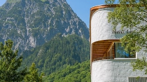 Un edificio cilindrico con un balcone, con l'insegna "Hotel Lu", sullo sfondo di montagne.