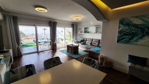 Un salon moderne comprenant un coin repas, de grandes portes-fenêtres coulissantes donnant sur une terrasse extérieure et une vue sur le paysage urbain.