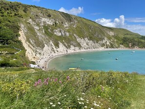 Eine Küstenlandschaft mit Strand, Klippen und einem Boot im Wasser.