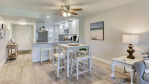 Une cuisine moderne avec des meubles blancs, un îlot central et un ventilateur de plafond.
