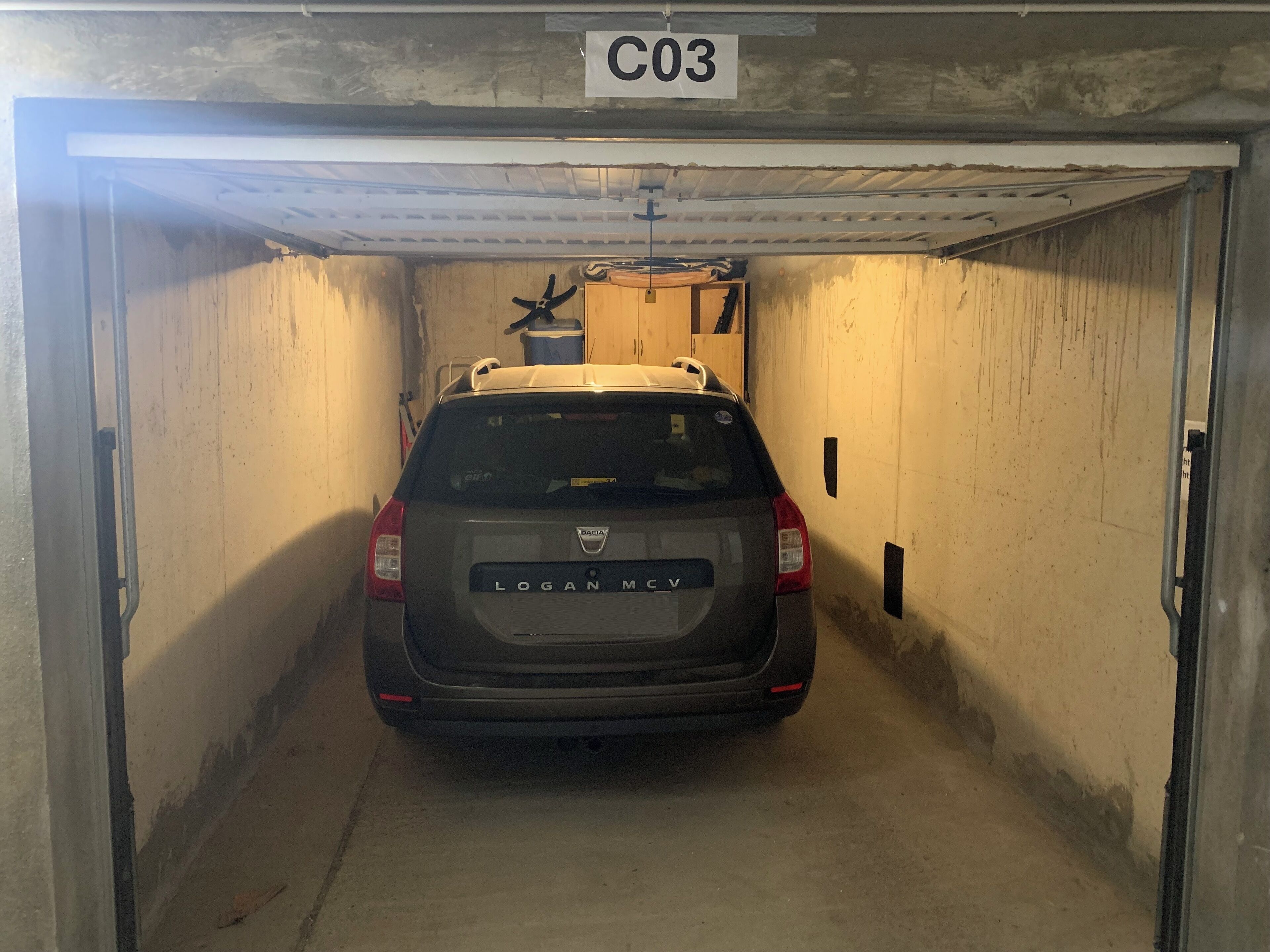 Ein Auto steht in einer Garage, an der Decke ist ein Schild mit der Aufschrift "C03".