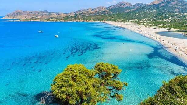 A coastal landscape with clear blue waters, a sandy beach, and a mountainous backdrop. - Family Vacation Apartment with Panoramic Sea View (Calvi)