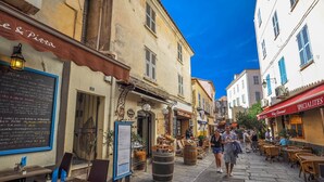 A narrow street with outdoor seating at cafes, stone pavement, and traditional European architecture. - Family Vacation Apartment with Panoramic Sea View (Calvi)