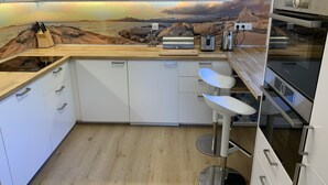 A modern kitchen with white cabinets, a wooden countertop, a Bosch oven, a toaster, and a sink. - Family Vacation Apartment with Panoramic Sea View (Calvi)