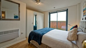 Une chambre avec un grand lit, une fenêtre, un radiateur et un miroir au mur.